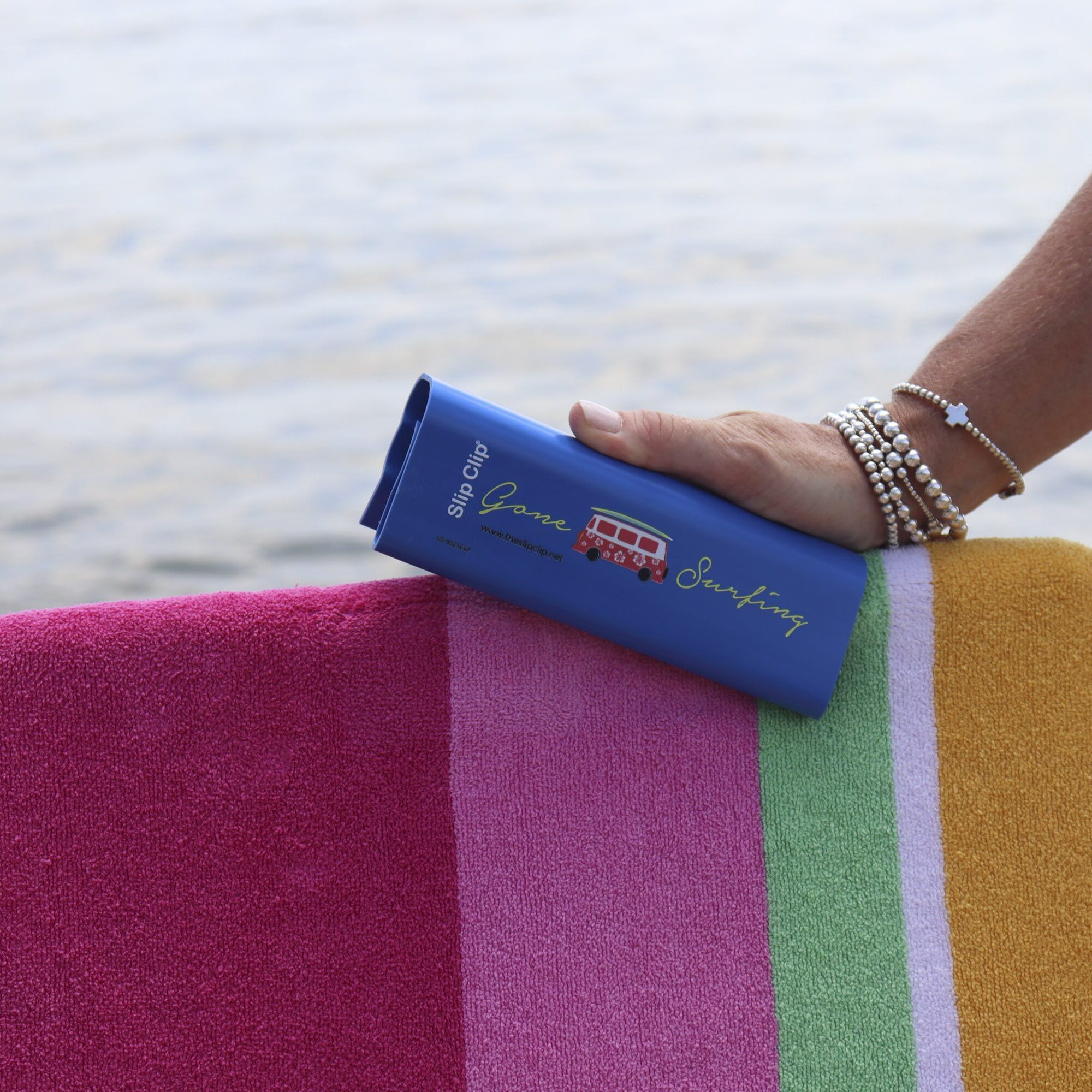 Hand holding sunscreen on striped beach towel